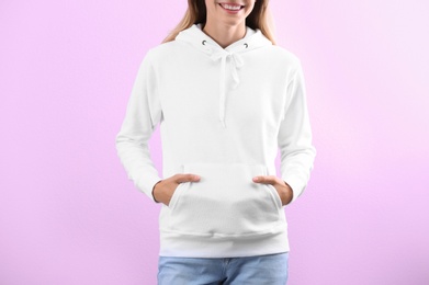 Woman in hoodie sweater on color background. Space for design