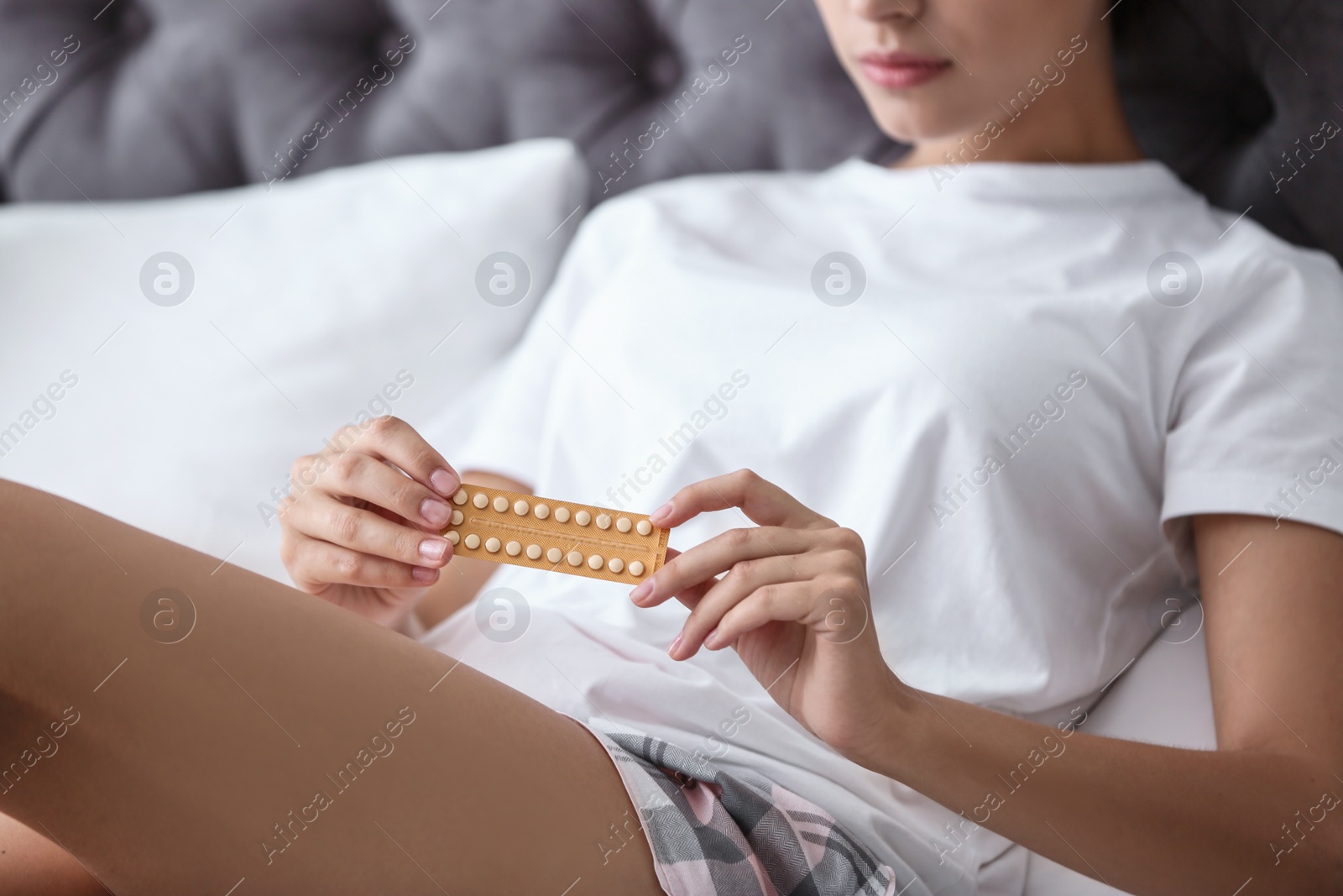 Photo of Young woman with birth control pills in bedroom. Gynecology