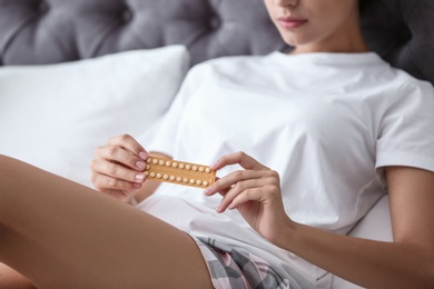 Photo of Young woman with birth control pills in bedroom. Gynecology