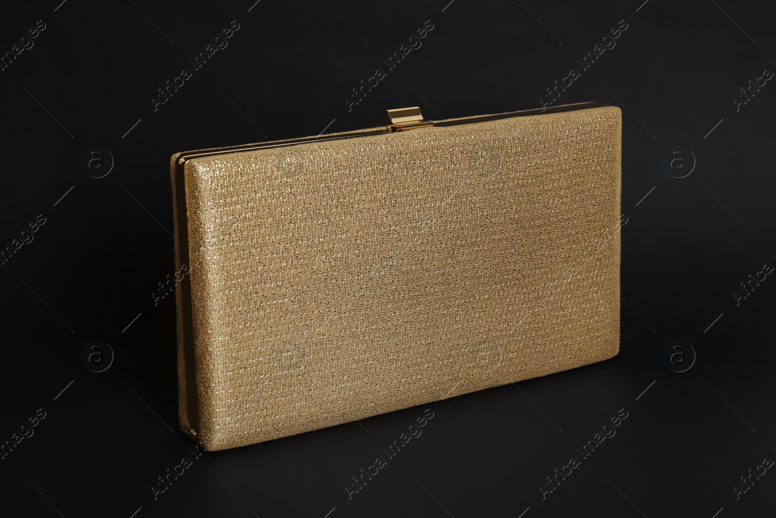 Photo of Elegant new gold clutch on black background