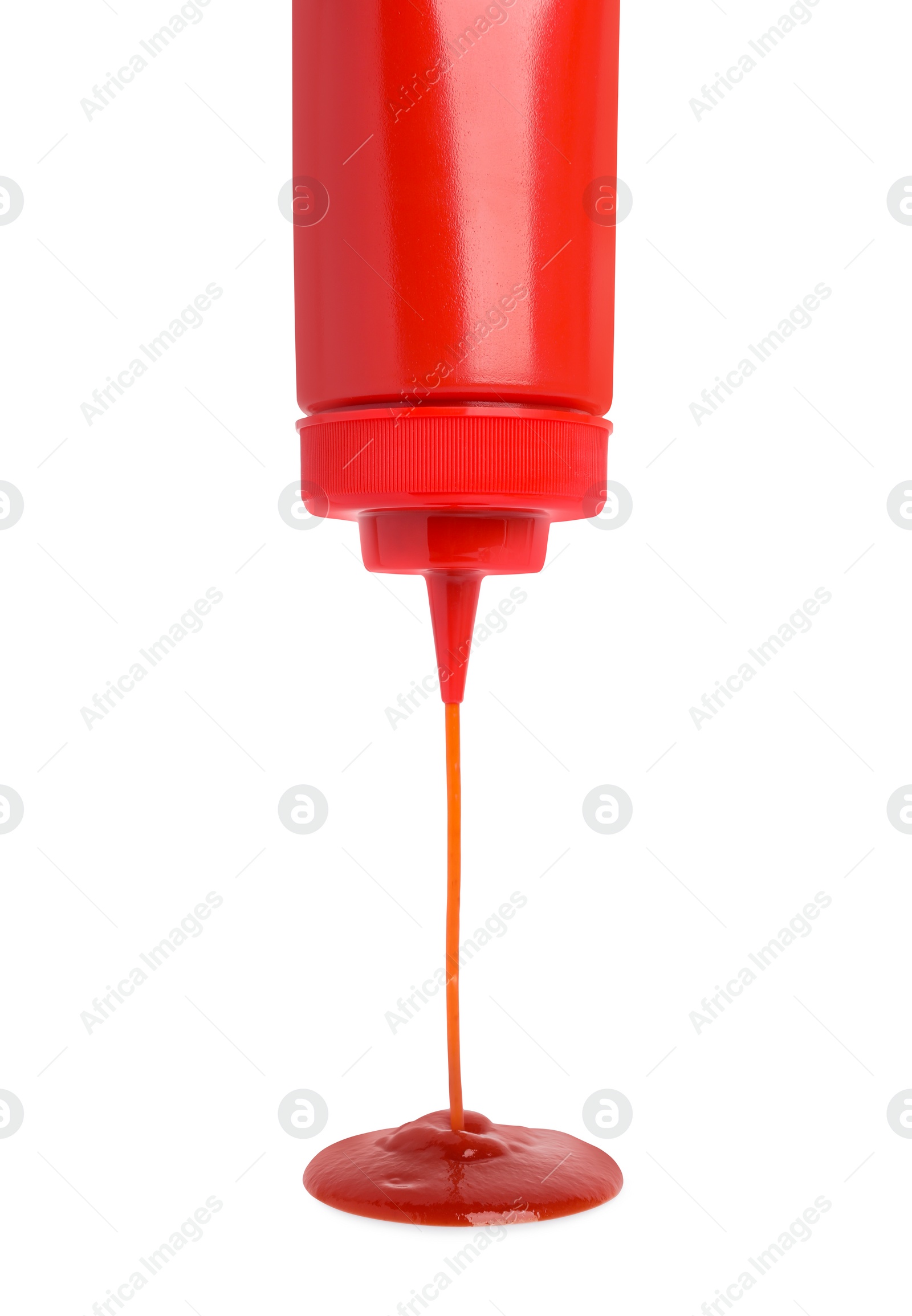 Photo of Pouring tasty red ketchup from bottle isolated on white