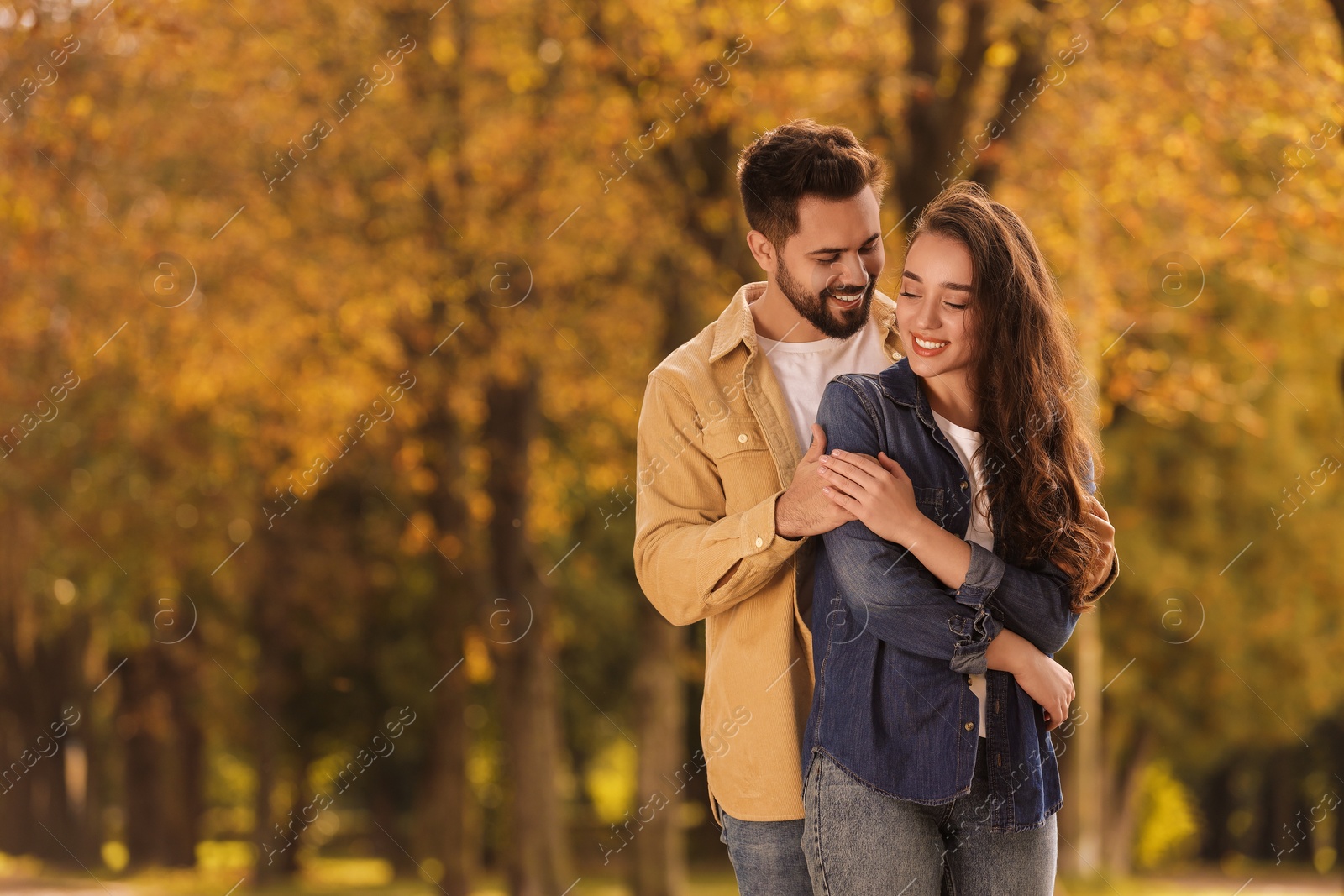 Photo of Beautiful couple spending time together in autumn park, space for text