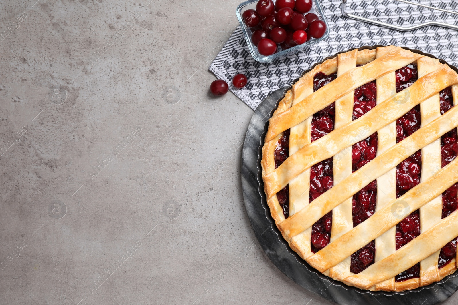 Photo of Delicious fresh pie and cherries on grey table, flat lay. Space for text