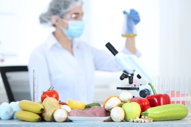 Photo of Fresh vegetables, fruits, meat on table and scientist proceeding quality control in laboratory