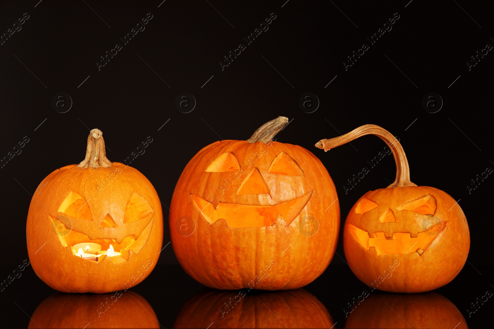 Photo of Halloween pumpkin heads. Glowing jack lanterns on dark background