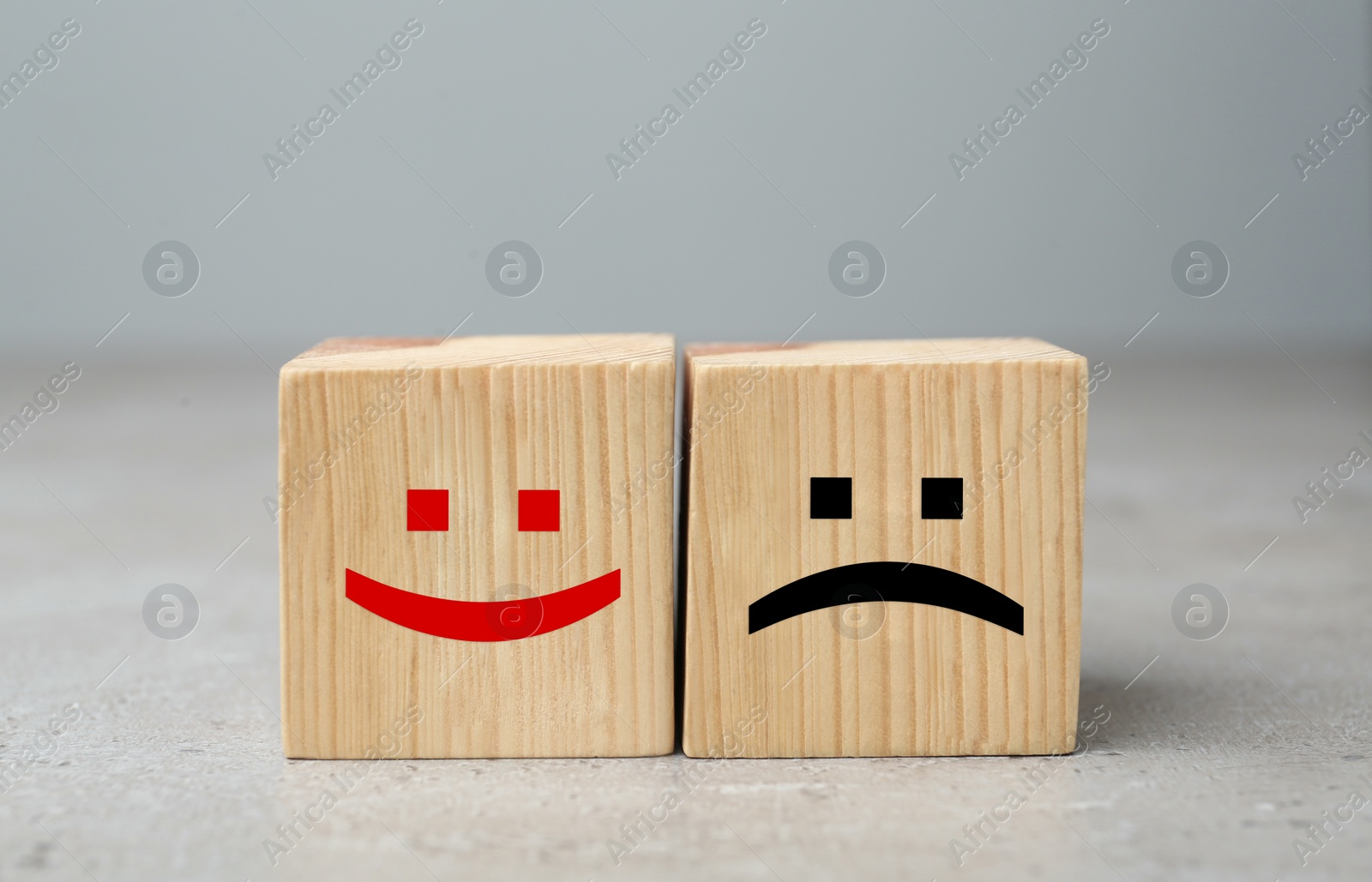 Image of Wooden cubes with happy and sad faces on grey table