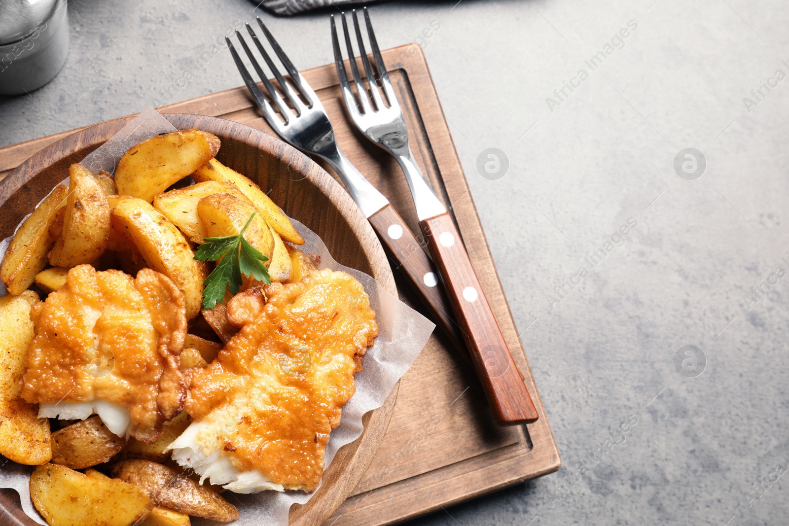 Photo of Wooden plate with British traditional fish and potato chips on table. Space for text