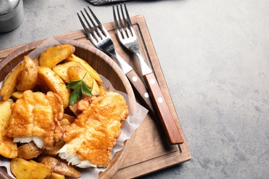 Photo of Wooden plate with British traditional fish and potato chips on table. Space for text