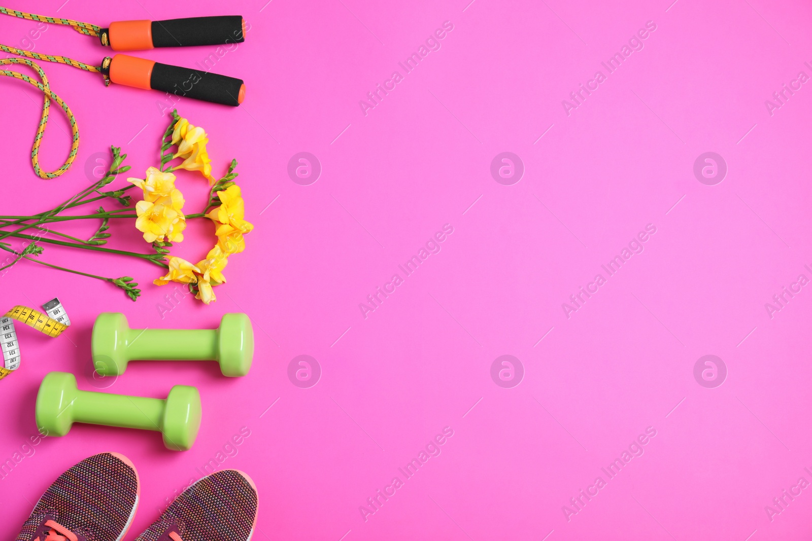 Photo of Flat lay composition with spring flowers and sports items on pink background. Space for text