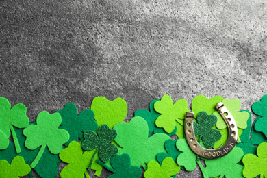 Flat lay composition with clover leaves and horseshoe on grey stone background, space for text. St. Patrick's day