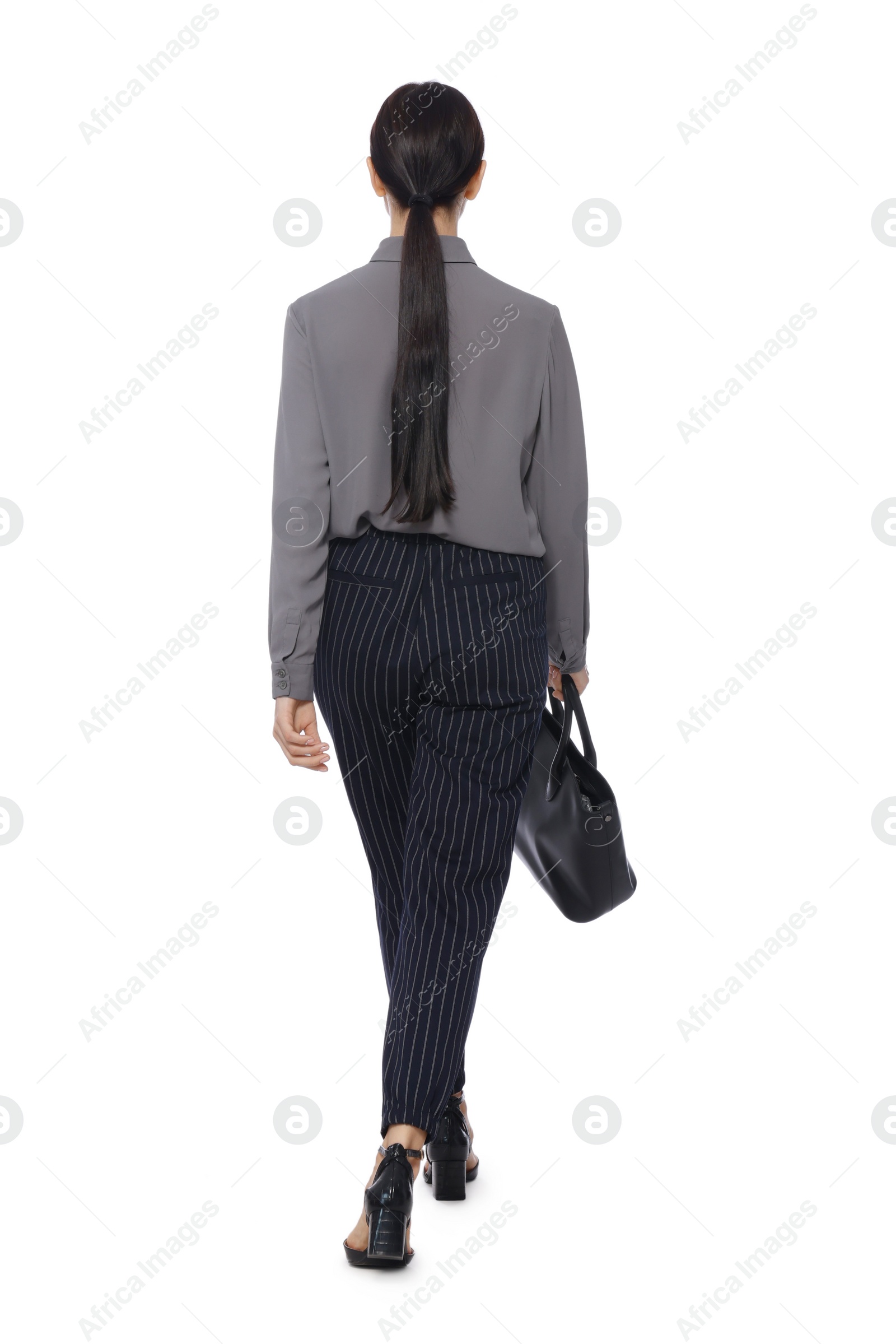 Photo of Young businesswoman with leather bag walking on white background, back view