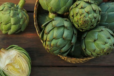 Whole and cut fresh raw artichokes on wooden table, flat lay