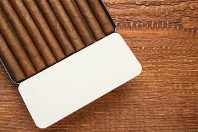 Photo of Humidor with cigars on wooden table, top view. Space for text