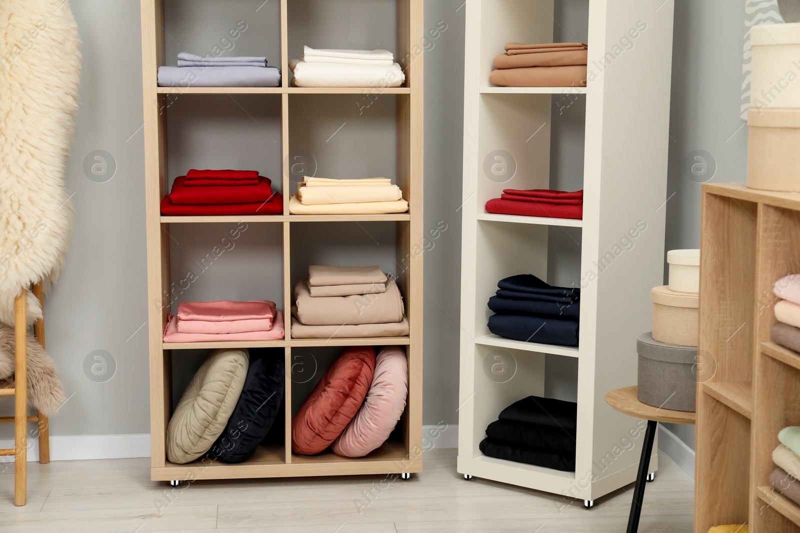 Photo of Different colorful bed linens and decorative boxes on display in home textiles store