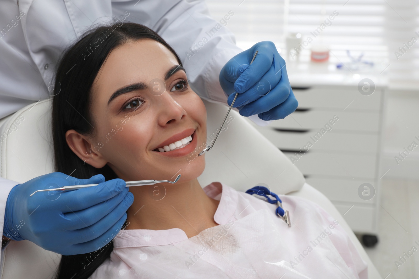 Photo of Dentist examining young woman's teeth in modern clinic