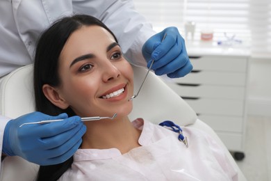 Dentist examining young woman's teeth in modern clinic