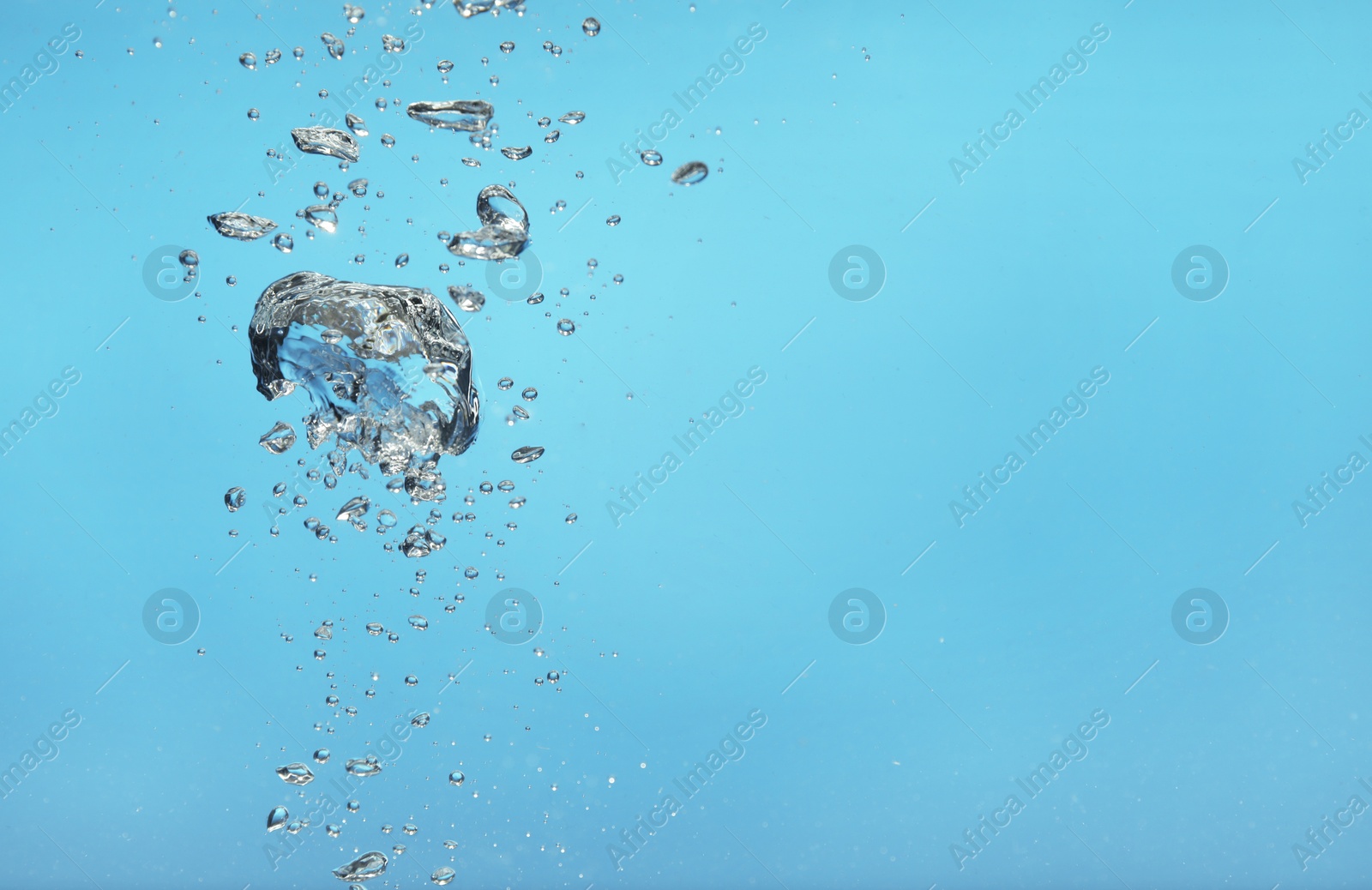 Photo of Air bubbles in water on light blue background. Space for text