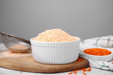 Photo of Bowl of lentil flour and seeds on white wooden table, space for text