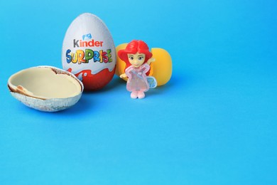Photo of Slynchev Bryag, Bulgaria - May 25, 2023: Kinder Surprise Eggs, plastic capsule and toy on light blue background, space for text