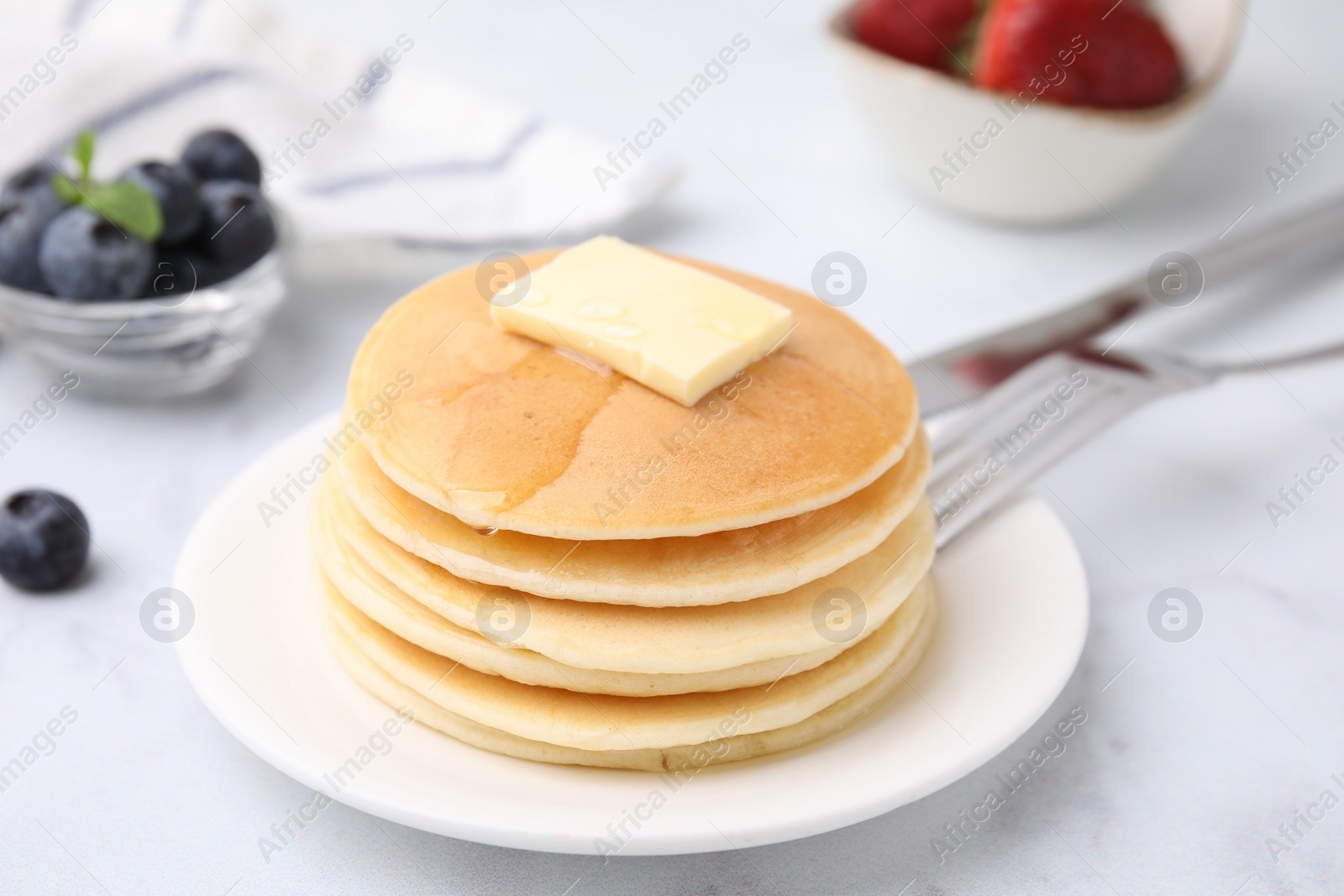 Photo of Delicious pancakes with butter and honey on white marble table, closeup