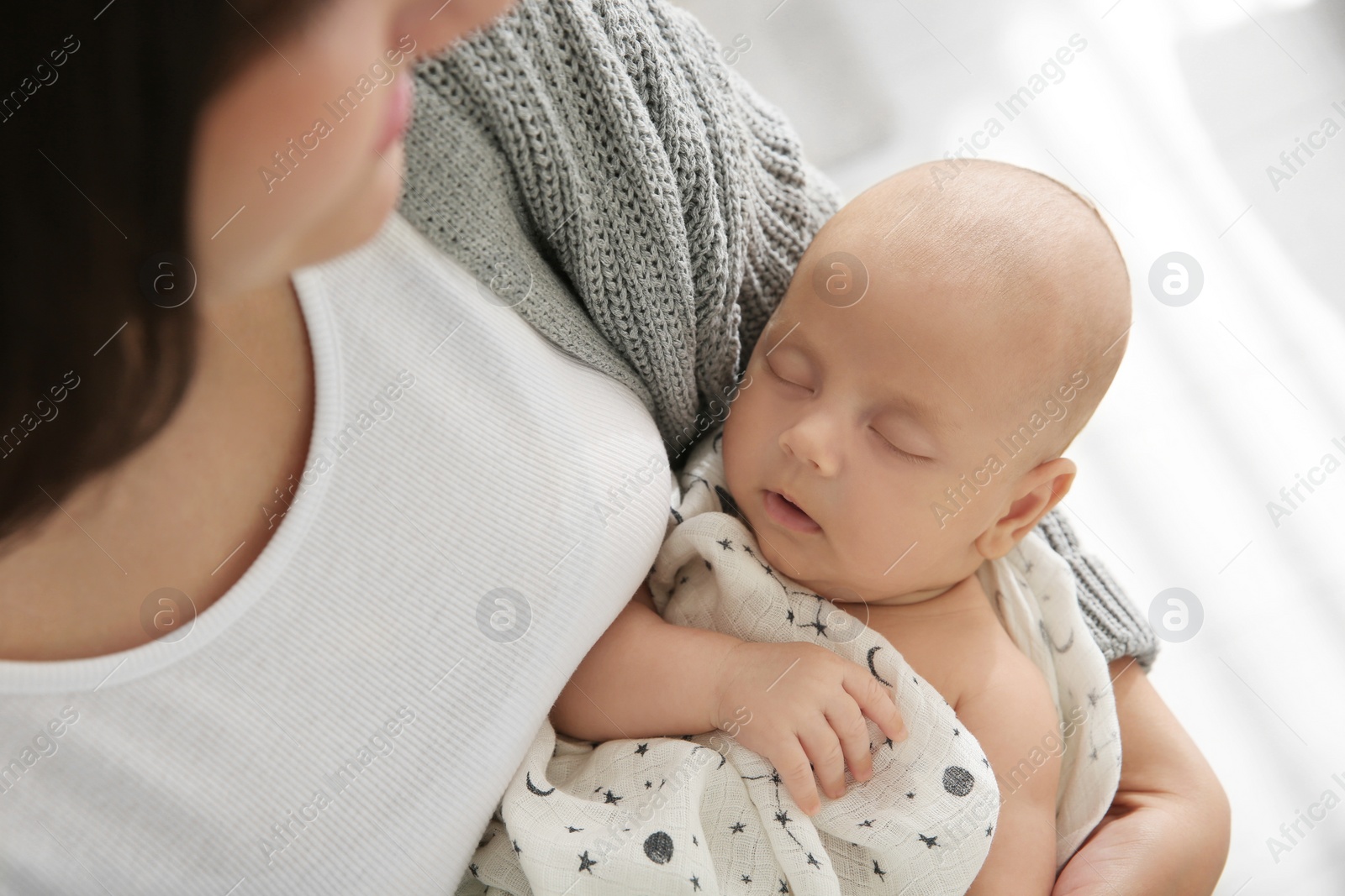 Photo of Mother holding her sleeping baby indoors, above view