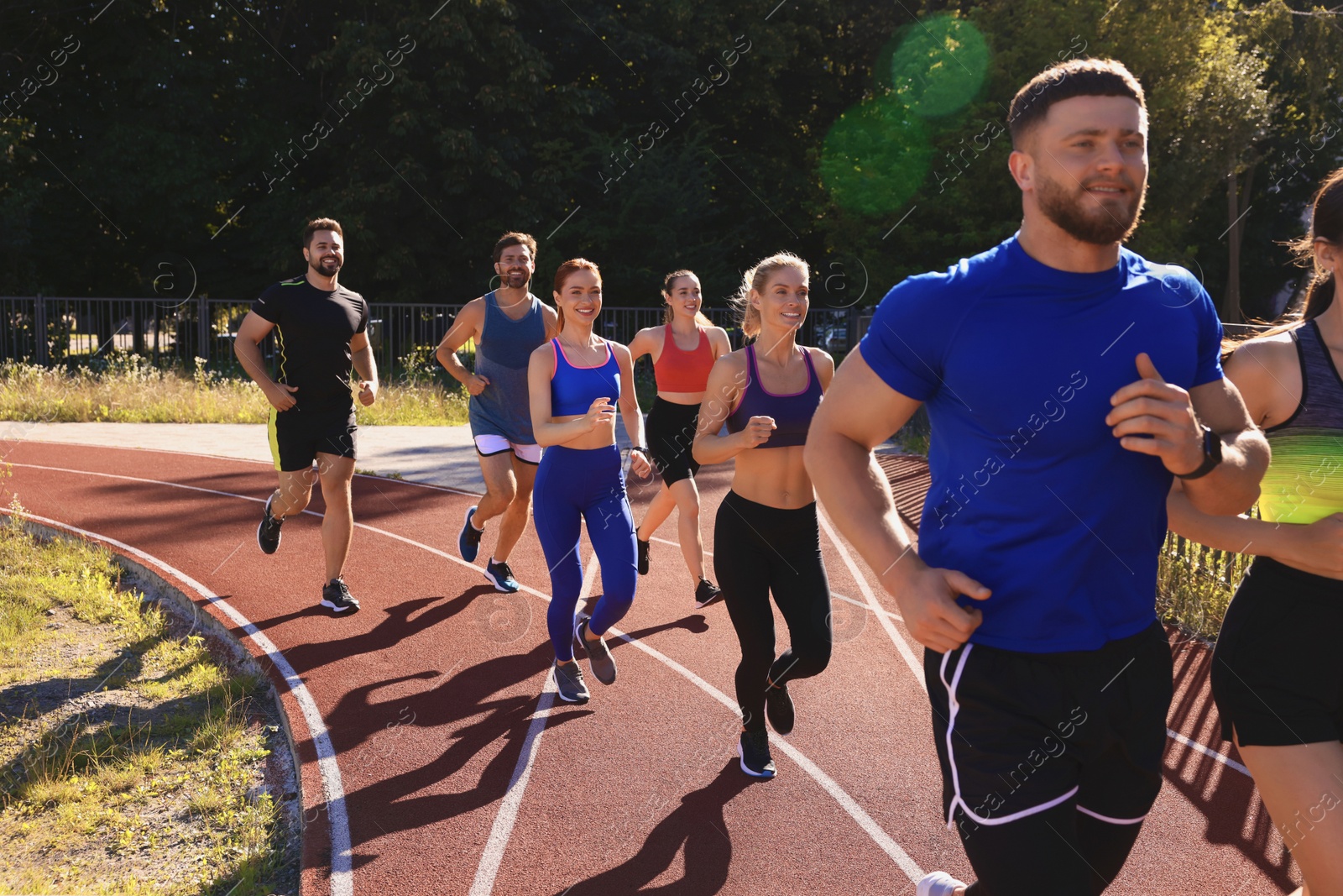 Photo of Group of people running at stadium on sunny day