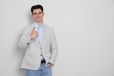 Photo of Handsome young man showing thumb up on white background, space for text