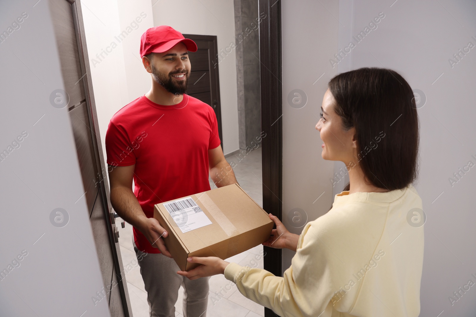 Photo of Woman receiving parcel from courier at home