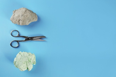 Photo of Flat lay composition with rock, paper and scissors on light blue background. Space for text