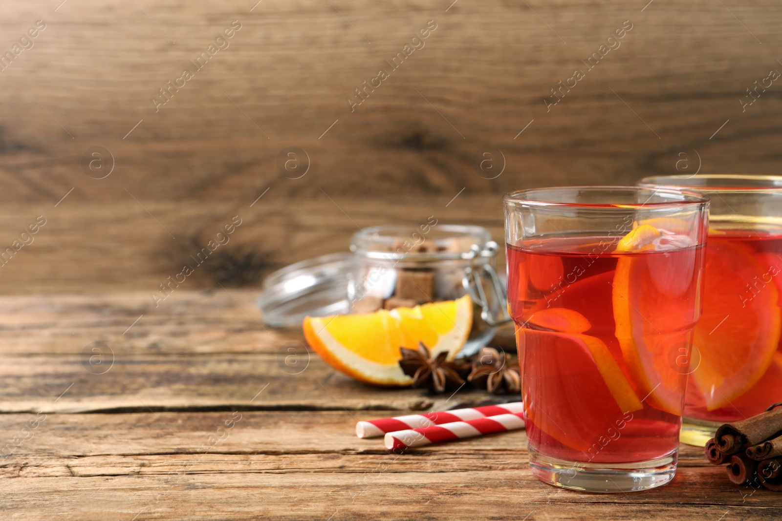 Photo of Aromatic punch drink and ingredients on wooden table. Space for text