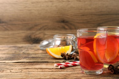 Photo of Aromatic punch drink and ingredients on wooden table. Space for text