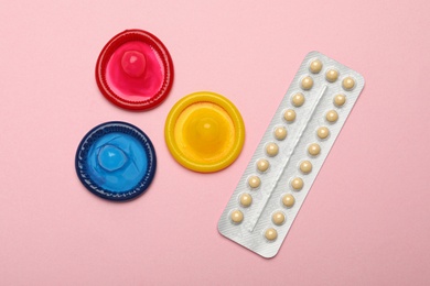 Photo of Condoms and birth control pills on pink background, top view. Safe sex