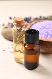 Photo of Bowl of sea salt, essential oil and lavender flowers on white wooden table, closeup