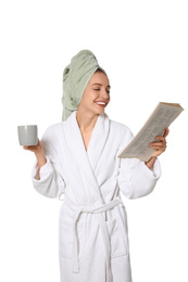 Beautiful young woman in bathrobe reading newspaper on white background