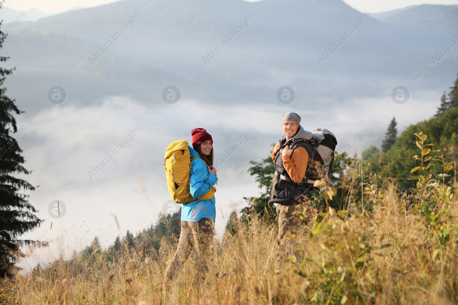 Photo of Tourists with backpacks hiking in foggy mountains