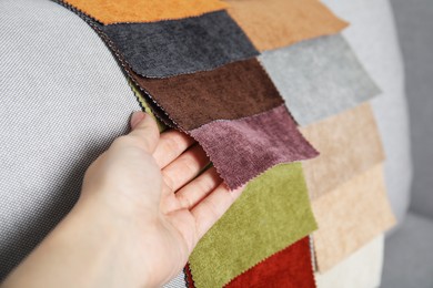 Photo of Woman choosing fabric among colorful samples on grey sofa, closeup