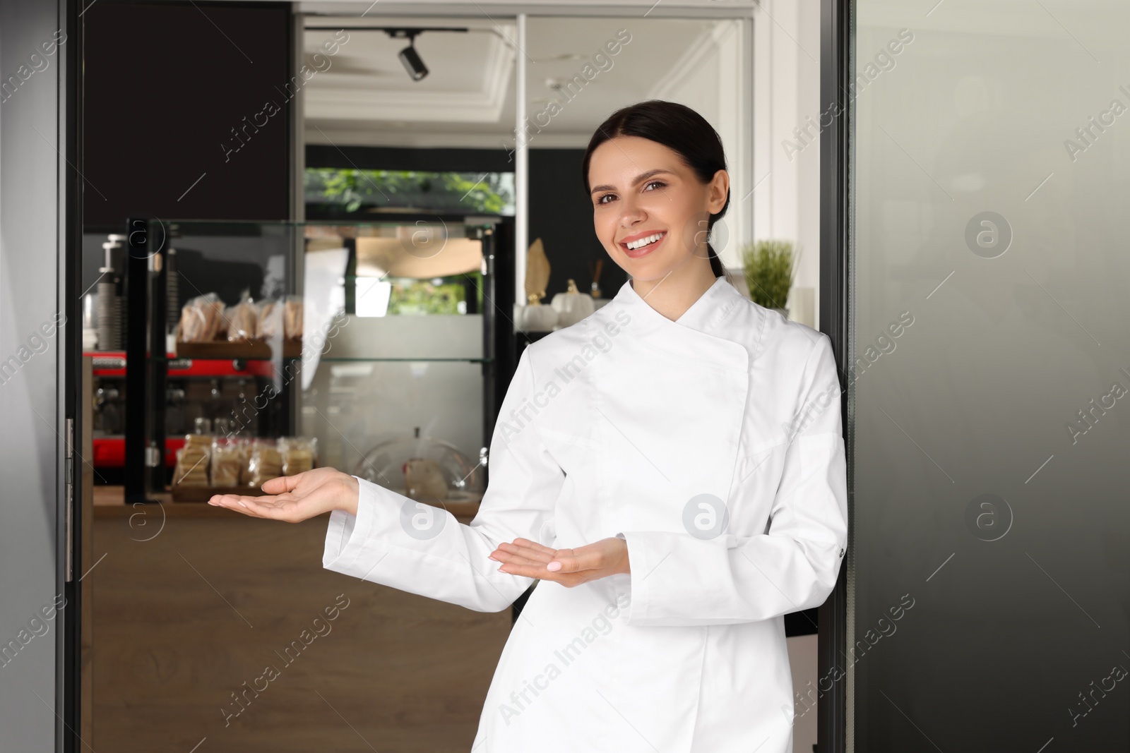 Photo of Happy baker in uniform at door of her cafe