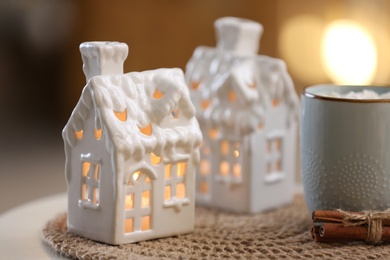 Photo of Composition with house shaped candle holder on white table against blurred background. Christmas decoration