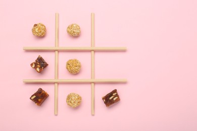 Photo of Tic tac toe game made with sweets on pink background, top view. Space for text