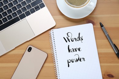 Notebook with phrase Words Have Power, smartphone, laptop, coffee and pen on wooden table, flat lay