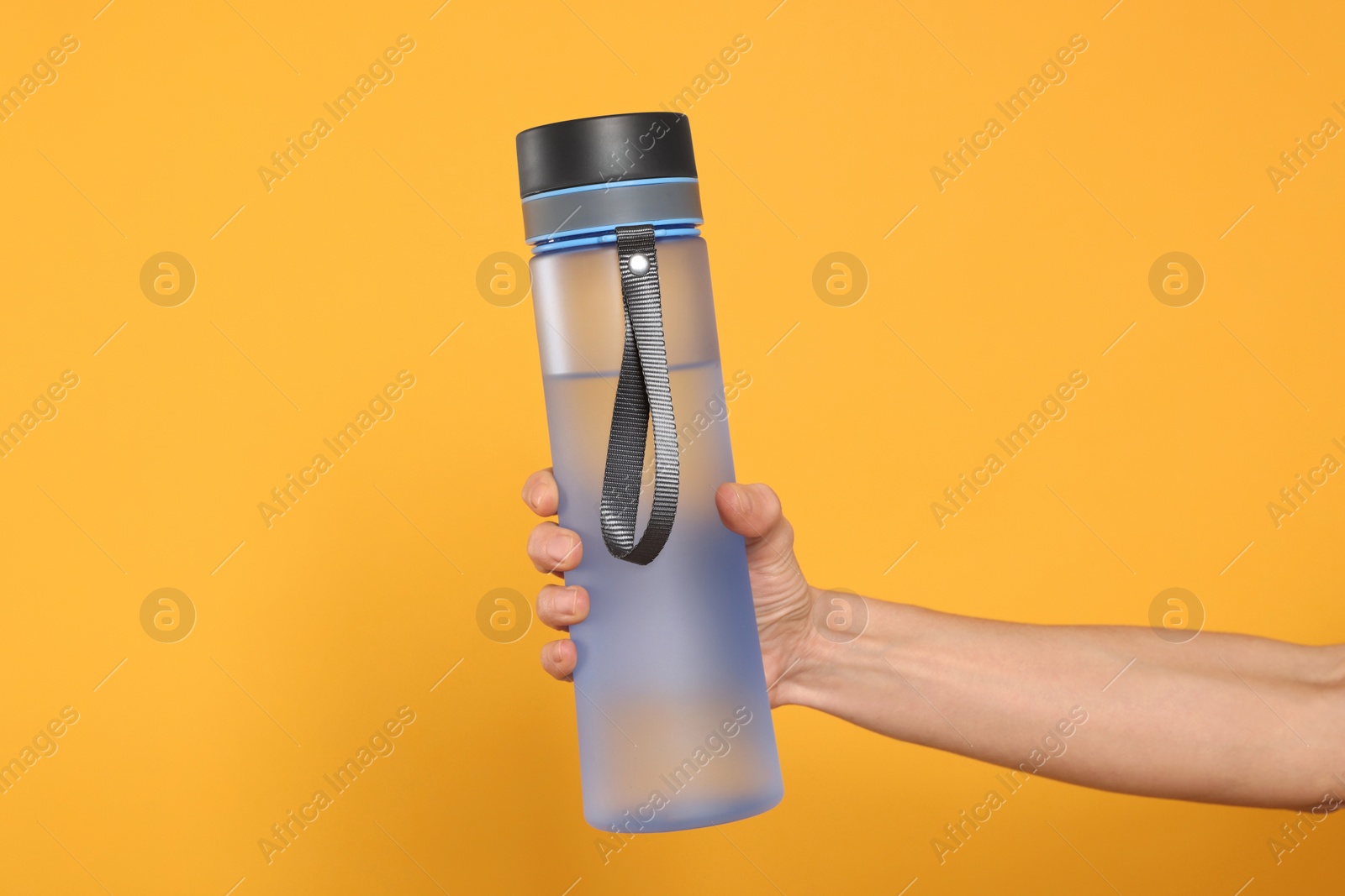 Photo of Woman holding bottle of drink on orange background, closeup