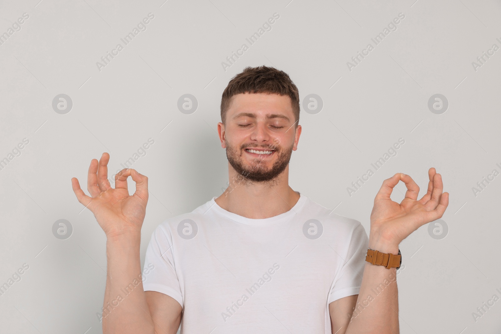 Photo of Young man meditating on white background. Zen concept