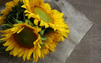 Photo of Beautiful sunflowers and cloth on wooden table. Space for text