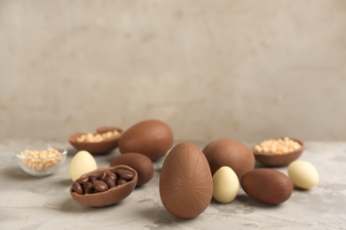 Sweet chocolate eggs and candies on grey marble table. Space for text