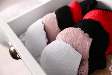Drawer with beautiful lace bras, closeup. Stylish underwear