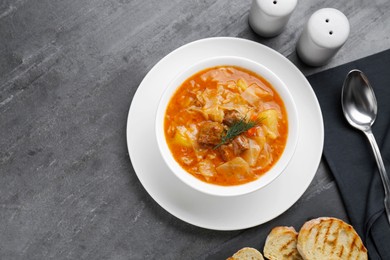 Tasty cabbage soup with meat, carrot and dill served on black table, flat lay. Space for text