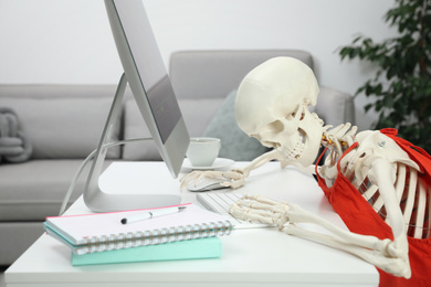 Human skeleton in red dress using computer at home
