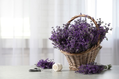 Fresh lavender flowers in basket on stone table indoors, space for text