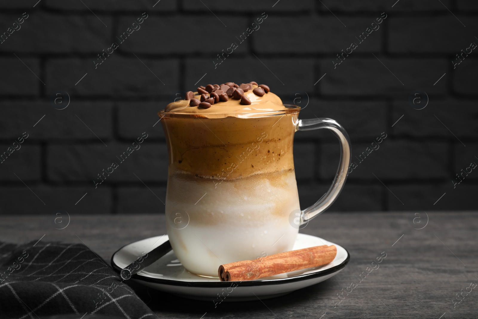 Photo of Delicious dalgona coffee and cinnamon stick on grey table