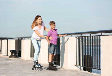 Photo of Mother and son roller skating on city street